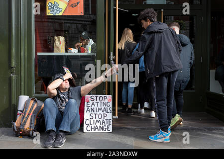 Ein Food science Demonstrant sitzt außerhalb einer McDonalds Restaurant in Whitehall während der Umweltschutz Protest über den Klimawandel Besetzung des Trafalgar Square in Central London, ist der dritte Tag der zwei Wochen anhaltenden weltweiten Protest von Mitgliedern des Aussterbens Rebellion, am 9. Oktober 2019, in London, England. Stockfoto
