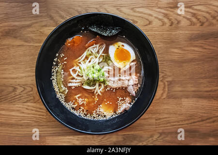 Traditionelle japanische Ramen Suppe auf dem hölzernen Tisch, Ansicht von oben Stockfoto