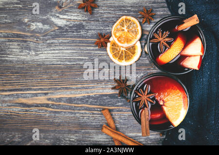 Weihnachten Glühwein mit Gewürzen, Orangenscheiben, Zimtstangen auf rustikalen Holztisch. Traditionelle Getränk auf Winterurlaub. Stockfoto