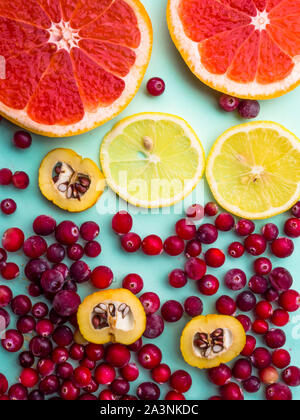 Schönen frischen in Scheiben geschnittenen gemischt Zitrusfrüchte als Hintergrund mit roten Cranberries, Cydonia auf blauem Hintergrund, Konzept der gesunden Ernährung, Diäten, top vie Stockfoto