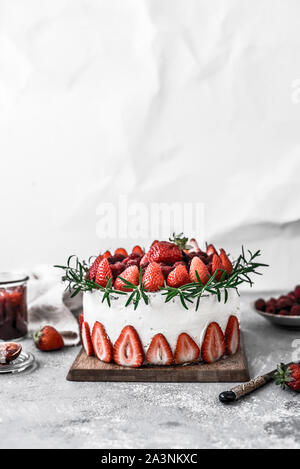 Kuchen mit Erdbeeren und Sahne und Erdbeermarmelade, serviert auf einem Holzbrett. Weißer Hintergrund. Stockfoto