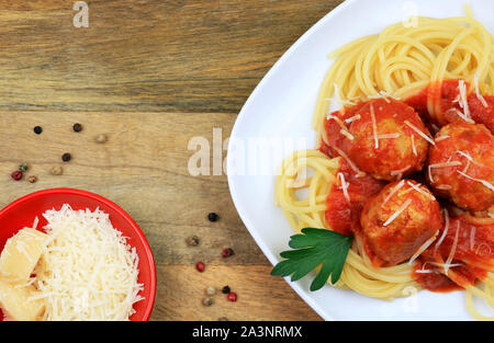 Italienische Küche. Spaghetti mit Fleischbällchen, Pasta mit Tomatensauce und geriebenem Parmesan auf rustikalen Holzmöbeln Hintergrund Platte. Ansicht von oben Stockfoto