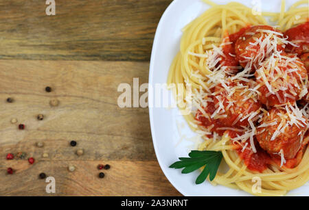 Italienische Küche. Spaghetti mit Fleischbällchen, Pasta mit Tomatensauce und geriebenem Parmesan auf rustikalen Holzmöbeln Hintergrund Platte. Ansicht von oben Stockfoto