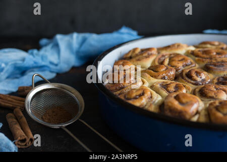 Cinnamon Roll Tarte mit Zuckersirup in vintage Backblech auf schwarzem Hintergrund Stockfoto