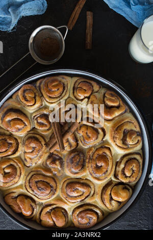 Cinnamon Roll Tarte mit Zuckersirup in vintage Backblech auf schwarzem Hintergrund Stockfoto