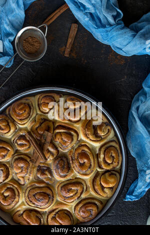 Cinnamon Roll Tarte mit Zuckersirup in vintage Backblech auf schwarzem Hintergrund Stockfoto