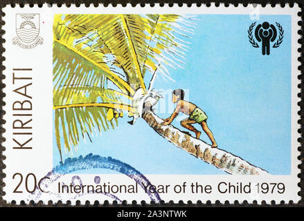 Junge klettern eine Palme auf Briefmarke von Kiribati Stockfoto