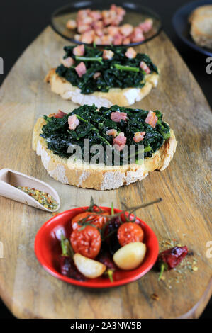 Konzept der italienisches Essen. Bruschetta mit schwarzen Kraut und Speck auf Holztisch. Rustikale italienische Beilage Stockfoto