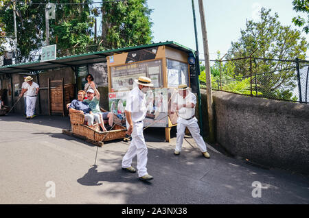 Monte, Madeira, Portugal - 14.September 2019: Weidenkorb Schlitten Treiber, Carreiros do Monte, fahren Touristen bergab. Traditionelle Transportmittel, heute eine touristische Attraktion. Typische Strohhüte. Stockfoto