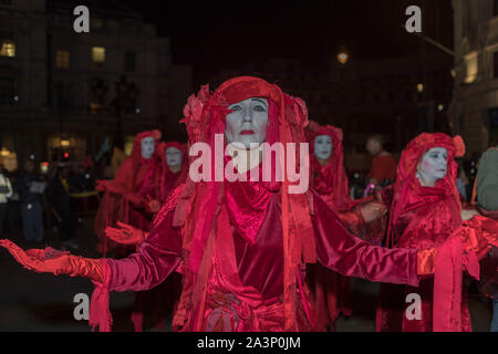 Trafalgar Square, London, Großbritannien. Oktober 2019. Aktivisten, die als Rote Rebellen verkleidet sind, führen während der Oktoberaufstand der Extinction Rebellion in Whitehall, London, einen stillen, theatralischen Protest durch. Die Gruppe, die in fließenden roten Kostümen und weißer Gesichtsfarbe verziert ist, symbolisiert Klimakummer und Dringlichkeit. Diese nächtliche Demonstration war Teil der Kampagne der Internationalen Rebellion, bei der die Teilnehmer Straßen blockierten und visuelle Interventionen inszenierten, um Maßnahmen der Regierung gegen die Klimakrise zu fordern. Penelope Barritt/Alamy Live News Stockfoto
