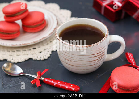 Eine Tasse Kaffee auf einem dunklen Hintergrund mit makronen der Koralle Farbe Stockfoto