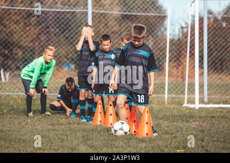 Fußball-Camp für Kids. Kinder Training Fußball-Fähigkeiten mit Kugeln und Kegel. Fußball slalom Bohrer auf Fußball schnelles Dribbling verbessern Stockfoto