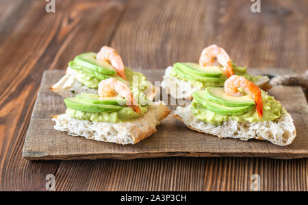 Sandwiches mit Guacamole, in Scheiben Avocado und Garnelen auf der Holzplatte Stockfoto