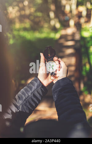 In der Nähe der weiblichen Händen hält Kompass gegen Wald Fußweg. Natur Orientierung Konzept. Stockfoto
