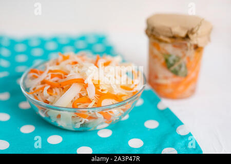 Ein Glas von Sauerkraut und Karotten im eigenen Saft mit Gewürzen, weiße Holztisch. Traditionelle, hausgemachte, fermentierte Gericht aus Russland und Deutschland Stockfoto