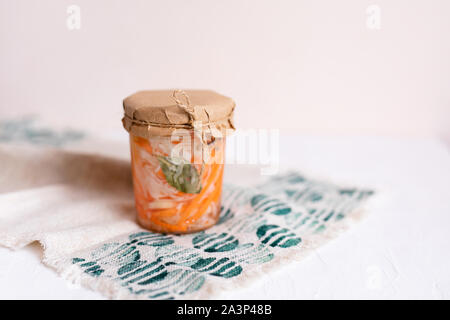 Ein Glas von Sauerkraut und Karotten im eigenen Saft mit Gewürzen, weiße Holztisch. Traditionelle, hausgemachte, fermentierte Gericht aus Russland und Deutschland Stockfoto