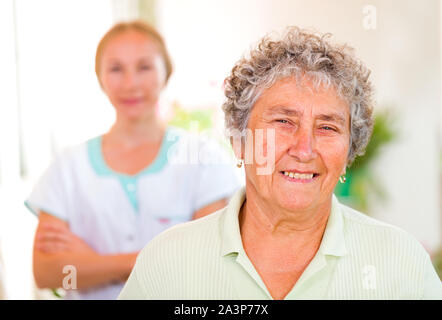Gerne ältere Frau mit ihrem Betreuer im Hintergrund Stockfoto