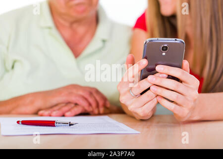 Junge Mädchen zeigen, wie das Smartphone zu ihrer Mutter zu verwenden Stockfoto