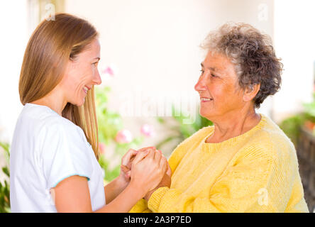 Foto der jungen Helfer, die die ältere Frau Hände Stockfoto