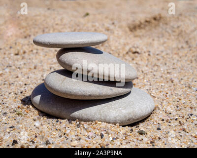 Ein Haufen Steine. Haufen von Steinen am Strand Sand gestapelt. Pastellfarben Textur durch helles Sonnenlicht beleuchtet. Stockfoto