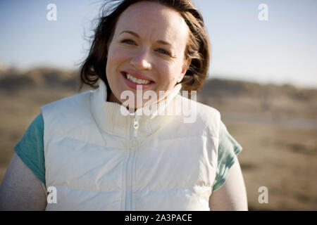 Porträt eines lächelnden Mitte der erwachsenen Frau am Strand. Stockfoto