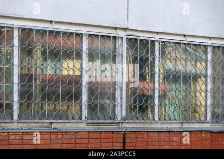 Dekorativer Sicherheit Gitter am Fenster mit sich wiederholenden Herzförmig und ein Detail des Alten zerbröckelt geknackt Verputzte Wand Stockfoto