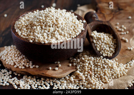 Raw weißen Sorghum Getreide in einer Schüssel auf einem Holztisch Stockfoto