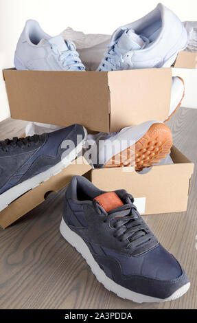 Turnschuhe in Kartons auf einer Holzplatte. Stockfoto