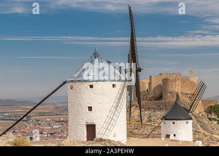 Landschaft in der spanischen Gemeinde Consuegra mit zwei alte Windmühle und das Schloss von La Muela im Hintergrund an einem Sommertag mit bewölktem Himmel Stockfoto