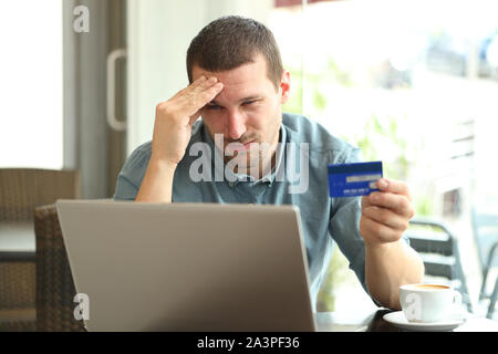 Frustrierter Mann bezahlen mit Kreditkarte und Laptop in einem Café sitzen Stockfoto