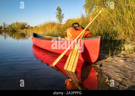 Rote tandem Kanu mit Holz Paddel und eine wasserdichte duffel an einem See, Ufer, Landschaft Stockfoto