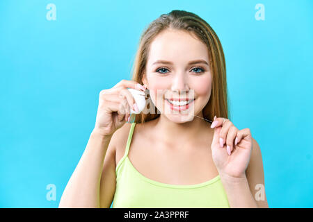 Junge schöne Frau ist bei der Reinigung der Zähne beschäftigt. Schönes Lächeln Gesunde weisse Zähne. Ein Mädchen hält einen Zahnseide. Das Konzept der Mundhygiene und Stockfoto