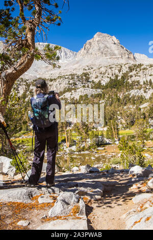 Eine Frau Landschaft Fotos mit ihrem iPhone auf einem Berg Trail in der östlichen Sierra Nevada, Kalifornien, USA Stockfoto