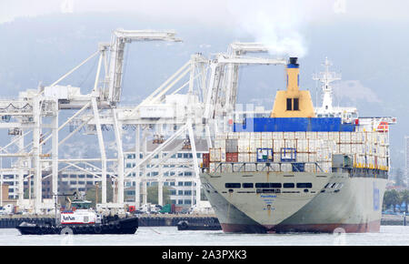 Oakland, CA - Juli 08, 2019: ein schubschiff Manöver Schiffe durch Anschieben oder Anschleppen. Mehrere Schlepper unterstützen Matson Frachtschiff MAHIMAHI in zu manövrieren Stockfoto