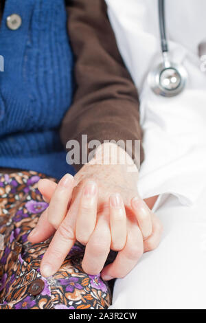 Junger Arzt hält die Hand der alten Frau Stockfoto