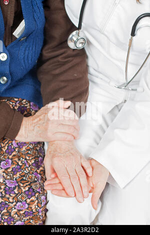 Junger Arzt hält die Hand der alten Frau Stockfoto