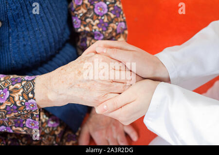 Junger Arzt hält die Hand der alten Frau Stockfoto