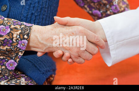 Junger Arzt hält die Hand der alten Frau Stockfoto