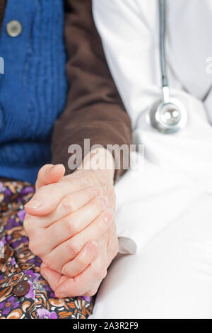 Junger Arzt hält die Hand der alten Frau Stockfoto