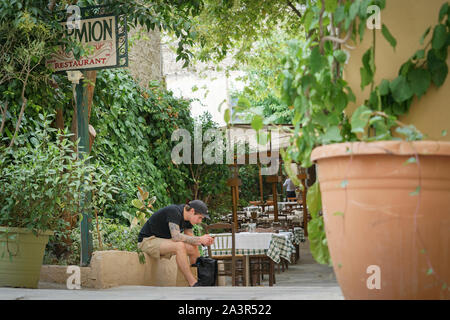 Athen Griechenland - 15. Juli 2019; Moderne junge Mann sitzt auf Schritt mit Mobile Stockfoto