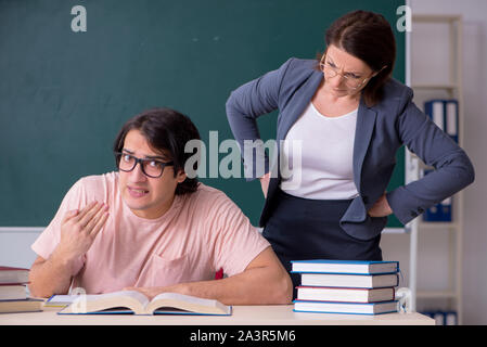 Die alte Lehrerin und männliche Schüler im Klassenzimmer Stockfoto