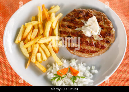 Traditionelle serbische pljeskavica, mit Kartoffeln, Pommes frites in Street Restaurant in Montenegro serviert, Nahaufnahme Stockfoto