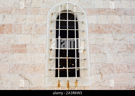 Mit Gitter in der alten Mauer der Kirche Fenster Stockfoto