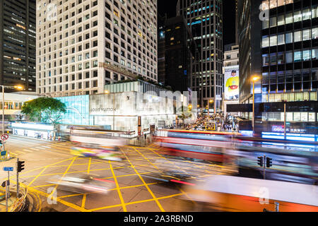 Hong Kong, China - 8. Oktober 2019: Bus und Pkw, aufgenommen mit der verschwommene Bewegung, hetzen durch ein wichtiger interesection im zentralen Geschäfts- und Einkaufsviertel Stockfoto