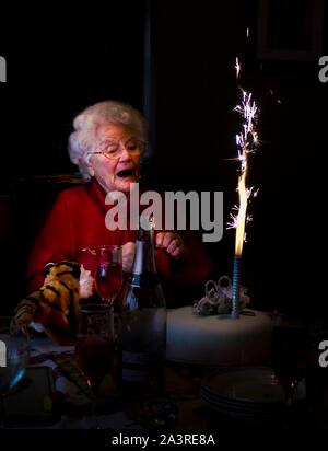 Ältere Dame überrascht von wunderkerze auf Geburtstag Stockfoto