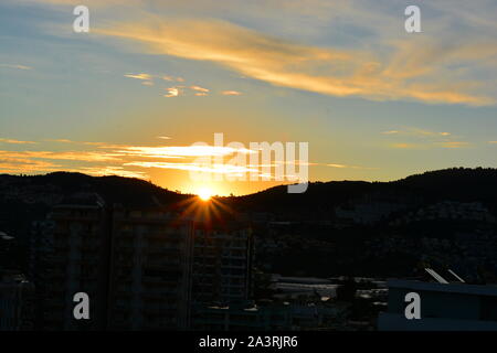 SUNRISE Mahmutlar, Alanya Türkei. Die Sonne über dem Kargicak Hügel und mahmutlar Dächer und Leuchtet der Himmel als der neue Tag beginnt. Stockfoto