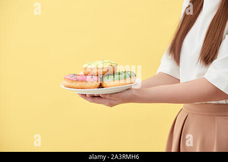 Asian Girl Show und Halteplatte voll mit lecker lecker aromatische Donuts in Smile Face isoliert. Stockfoto