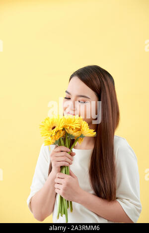 Asiatische Dame hält ein Bündel von Blume stehen gegen eine Wand. Stockfoto