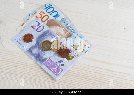Einige Schwedische Krone Banknoten und Münzen, die auf einer hölzernen Oberfläche Stockfoto