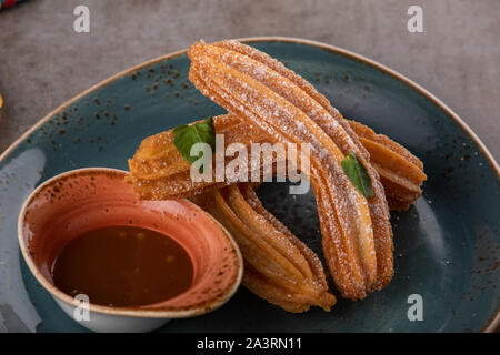 Churros mit Zucker und Schokoladensauce, Minze. Stockfoto